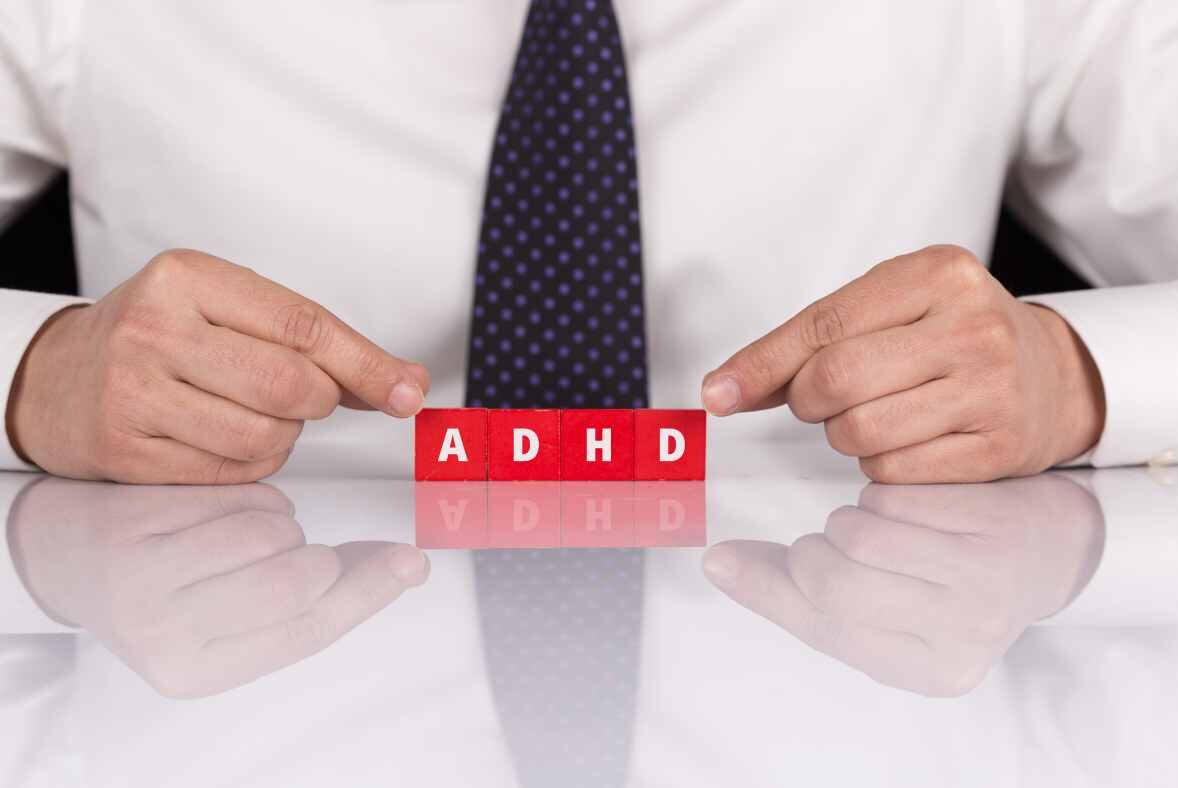 ADHD Sign in red with man pointing to it wearing tie - what type of therapist is best for ADHD