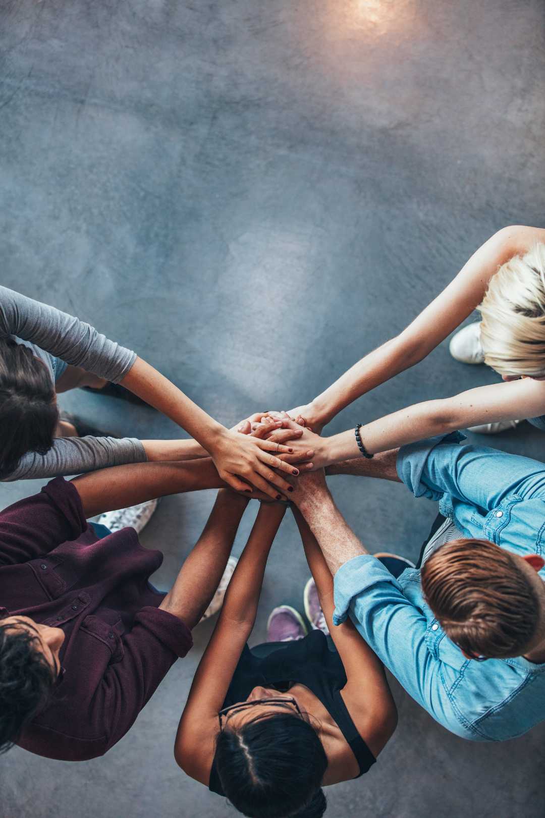 Rowan Center for Behavioral Health Career Opportunities Image showing a diverse set of hands together in unity with a concrete floor in the background