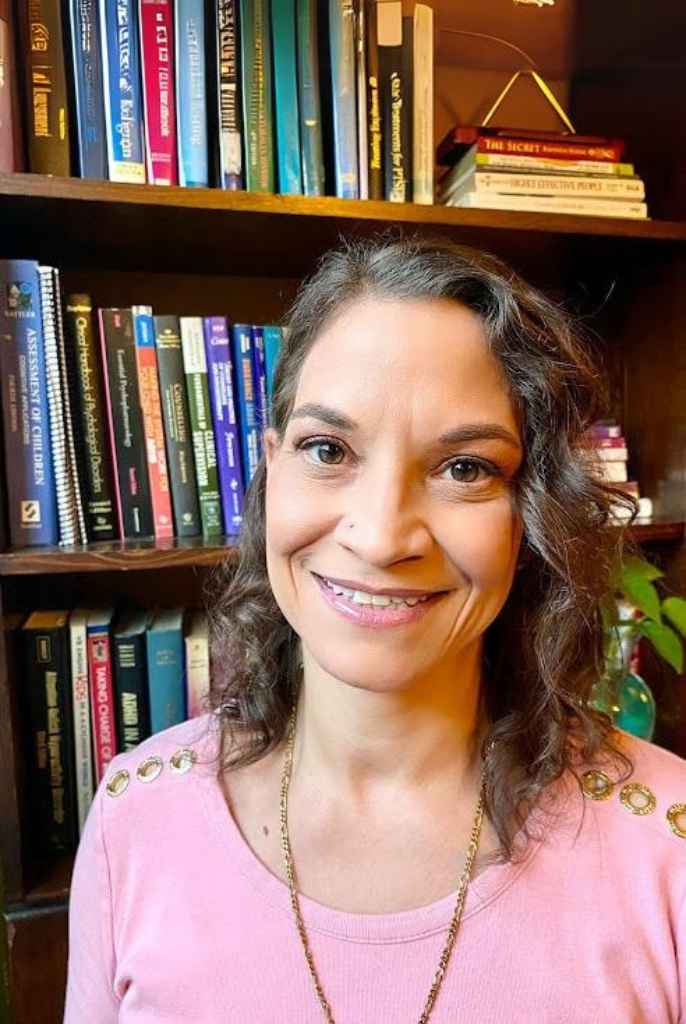 Dr. Amaya Rucker Profile Photo - Pink shirt in front of a bookcase - Rowan Center for Behavioral Medicine