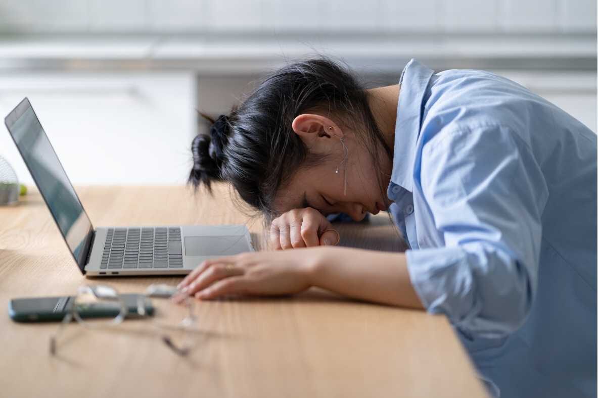 Recognizing and Addressing Burnout in Healthcare Professionals - Cover Photo Woman with head on desk exhausted