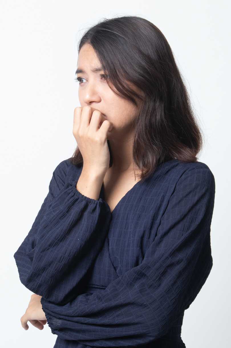 Woman with her hands on her mouth showing the face of someone experiencing anxiety